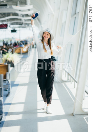 Cheerful businesswoman waiting for her flight at airport. Young woman at the airport. A young woman is waiting her flight in waiting hall in airport. Businesswoman waiting for her flight at airport. Cheerful businesswoman waiting for her flight at airport. Young woman at the airport. A young woman is waiting her flight in waiting hall in airport. Businesswoman waiting for her flight at airport. 87347654