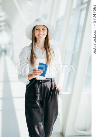 Cheerful businesswoman waiting for her flight at airport. Young woman at the airport. Travel. Attractive young woman going on a business trip. 87347662
