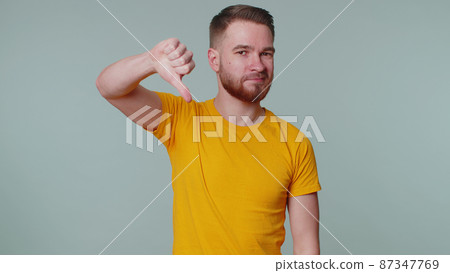 Upset man in casual t-shirt showing thumbs down sign gesture, disapproval, dissatisfied dislike Upset man in casual t-shirt showing thumbs down sign gesture, disapproval, dissatisfied dislike 87347769