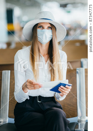 Elegant beautiful girl holding travel tickets and using a phone, happy girl looking at the camera in the airport terminal. Fashion woman portrait. Airport terminal. Business trip 87347775