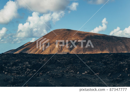 Amazing panoramic landscape of volcano craters in Timanfaya national park. Popular touristic attraction in Lanzarote island, Canary islans, Spain. Artistic picture. Beauty world. Travel concept. 87347777