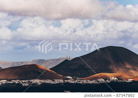 Amazing panoramic landscape of volcano craters in Timanfaya national park. Popular touristic attraction in Lanzarote island, Canary islans, Spain. Artistic picture. Beauty world. Travel concept. Amazing panoramic landscape of volcano craters in Timanfaya national park. Popular touristic attraction in Lanzarote island, Canary islans, Spain. Artistic picture. Beauty world. Travel concept. 87347802