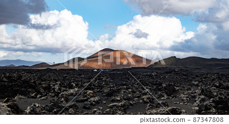 Amazing panoramic landscape of volcano craters in Timanfaya national park. Popular touristic attraction in Lanzarote island, Canary islans, Spain. Artistic picture. Beauty world. Travel concept. Amazing panoramic landscape of volcano craters in Timanfaya national park. Popular touristic attraction in Lanzarote island, Canary islans, Spain. Artistic picture. Beauty world. Travel concept. 87347808