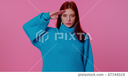 Responsible redhead girl giving salute listening to order as if soldier following discipline obeying Responsible redhead girl giving salute listening to order as if soldier following discipline obeying 87348028