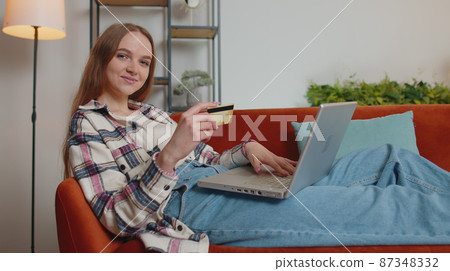 Woman sitting at home using credit bank card and laptop pc while transferring money online shopping Woman sitting at home using credit bank card and laptop pc while transferring money online shopping 87348332