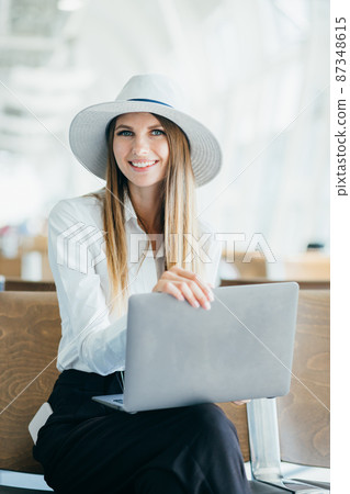 happy woman using laptop computer at airport. 87348615