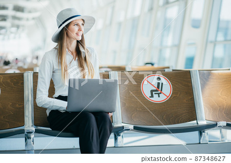Teenage girl is using a laptop to check email or social network or internet at the international airport to travel on weekends Teenage girl is using a laptop to check email or social network or internet at the international airport to travel on weekends 87348627