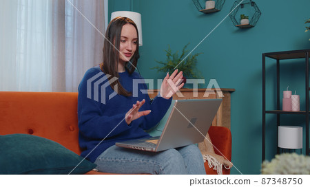 Woman freelance wear headphone make video call teaching tutoring talking on laptop at home office 87348750