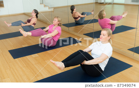 People relaxing and enjoying yoga elements - boat pose People relaxing and enjoying yoga elements - boat pose 87349074