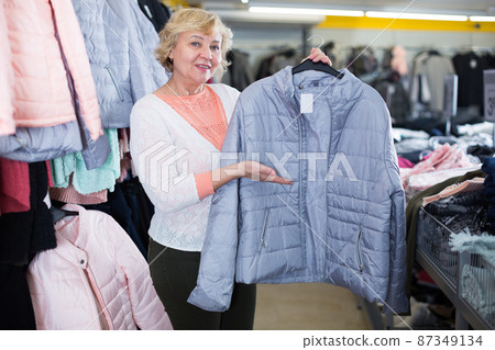 Mature woman buyer choosing windbreaker jacket Mature woman buyer choosing windbreaker jacket 87349134
