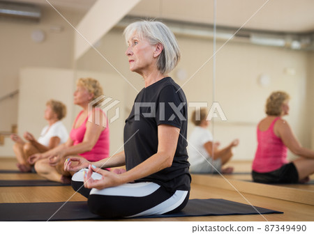 Group of mature women meditates in the half-lotus position 87349490
