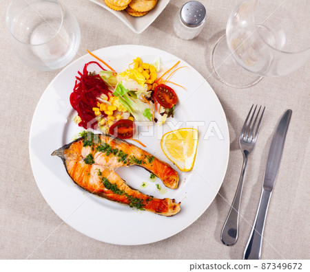 Roasted salmon steak with green sauce, vegetables and lemon Roasted salmon steak with green sauce, vegetables and lemon 87349672