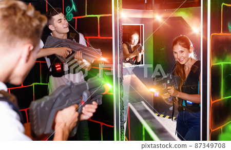 Laser tag players guys and girls playing in teams in dark laser Laser tag players guys and girls playing in teams in dark laser 87349708