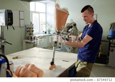 Worker of prosthetic production factory fixing upper part of leg prosthesis 87349712