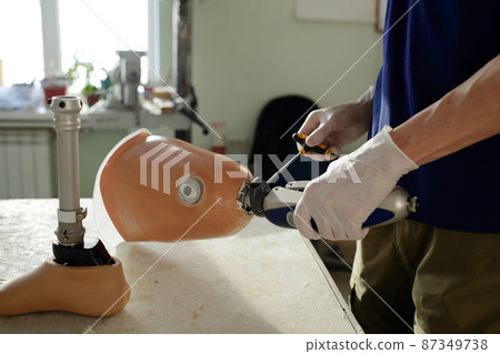 Gloved hands of manual worker fixing mechanism with screwdriver 87349738