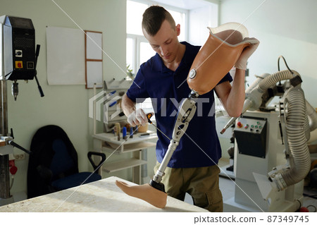 Young prosthetic production specialist assembling artificial leg Young prosthetic production specialist assembling artificial leg 87349745