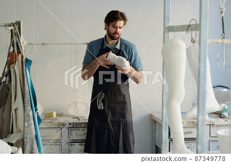 Young master of prosthetic manufactory looking at plaster cast Young master of prosthetic manufactory looking at plaster cast 87349778