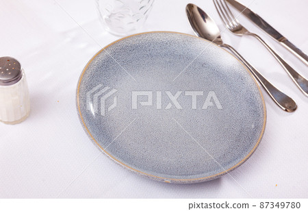 Empty plate and serving pieces on table Empty plate and serving pieces on table 87349780