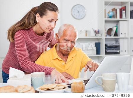 Mature man working at laptop, daughter trying to help him Mature man working at laptop, daughter trying to help him 87349836