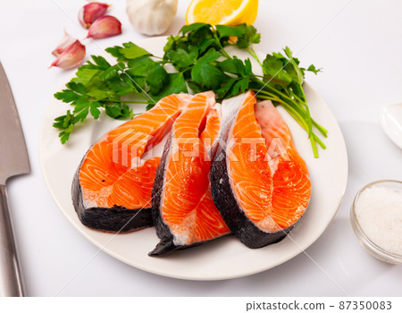 Raw salmon steaks with lemon, parsley, garlic Raw salmon steaks with lemon, parsley, garlic 87350083