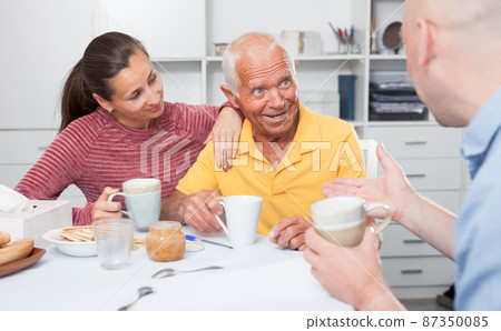 Portrait of mature man with daughter and friend talking at table Portrait of mature man with daughter and friend talking at table 87350085