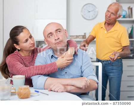 Couple hugging after conflict, worried elderly man on backgroud Couple hugging after conflict, worried elderly man on backgroud 87350090