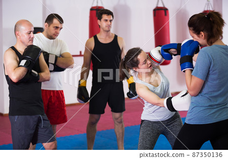 Sportswomen competing in colored boxing gloves Sportswomen competing in colored boxing gloves 87350136