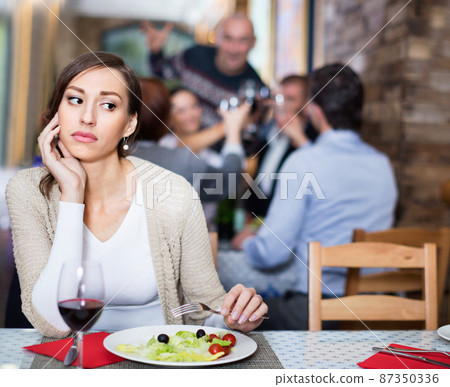 Portrait of upset woman in the restaurant with salad and wine Portrait of upset woman in the restaurant with salad and wine 87350336