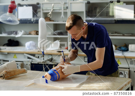 Worker of manufactory bending over table while putting marks on silicone liner 87350816