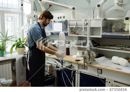 Worker of manufactory putting white sheet on workpiece of prosthetic socket Worker of manufactory putting white sheet on workpiece of prosthetic socket 87350856
