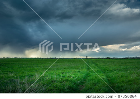 The road through the meadow and the rainy dark cloud The road through the meadow and the rainy dark cloud 87350864