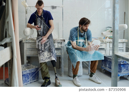 Two young male colleagues having short rest after work in prosthetic factory Two young male colleagues having short rest after work in prosthetic factory 87350906