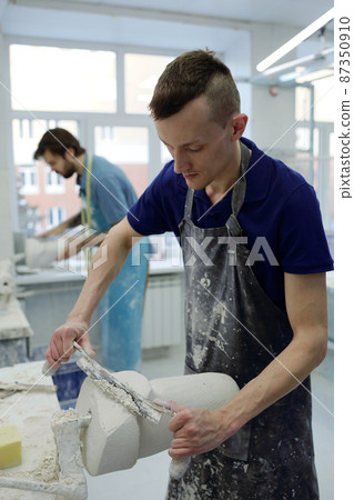 Worker of prosthetic factory cutting upper part of plaster cast 87350910