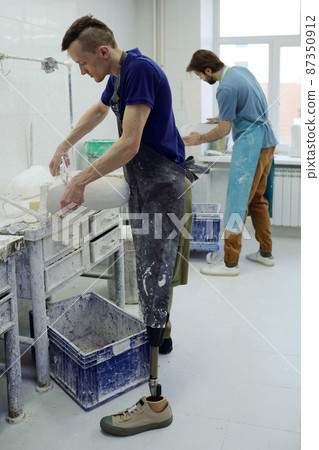 Young worker of contemporary prosthetic factory grinding plaster cast 87350912