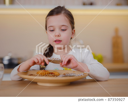 Happy little baby girl smiles happily when she eats cookies Happy little baby girl smiles happily when she eats cookies 87350927