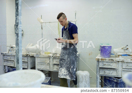 Young worker of prosthetic factory scrolling in smartphone Young worker of prosthetic factory scrolling in smartphone 87350934