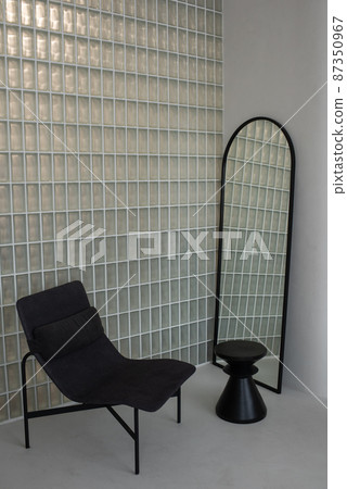 Corner of room in contemporary apartment with chair, mirror and small table Corner of room in contemporary apartment with chair, mirror and small table 87350967