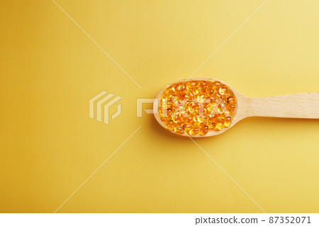 Vitamin D3 Capsules in a spoon with other vitamin D3 capsules around them on a yellow background Vitamin D3 Capsules in a spoon with other vitamin D3 capsules around them on a yellow background 87352071