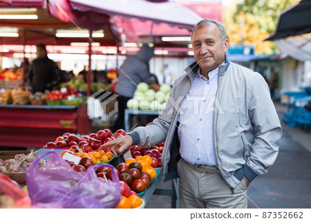 Man choosing vegetables in greengrocery Man choosing vegetables in greengrocery 87352662