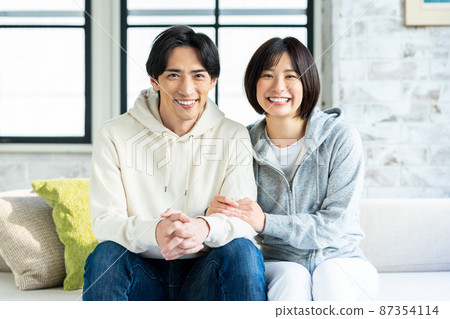 一對年輕夫婦在客廳裡放鬆 一對年輕夫婦在客廳裡放鬆 87354114