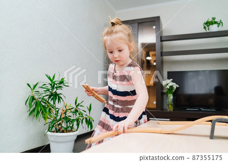 little girl plays with wooden toy railway.  87355175