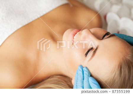 Beautiful girl has a facial massage in a beauty clinic. 87355199