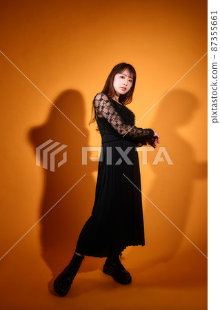 Young woman dressed in black with lights on an orange background 87355661