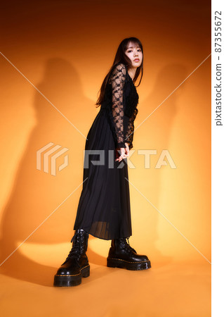 身著黑色衣服、橙色背景燈的年輕女子 87355672