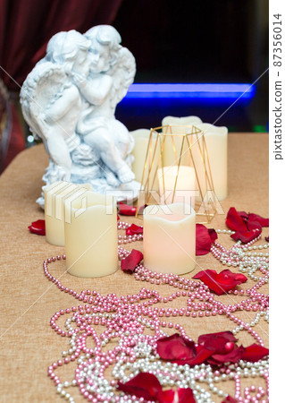 Angel figures, candles and rose petals, romantic dinner in a restaurant 87356014