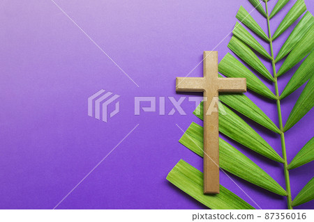 Cross and palm leaves on purple background. Lent season concept. Cross and palm leaves on purple background. Lent season concept. 87356016