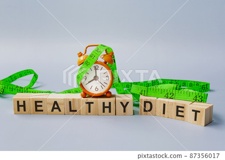 Healthy diet text on wooden block cube with measure tap and orange clock. Healthy diet text on wooden block cube with measure tap and orange clock. 87356017