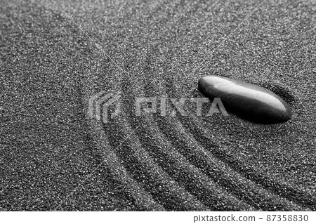 Zen garden stone on black sand with pattern, closeup Zen garden stone on black sand with pattern, closeup 87358830