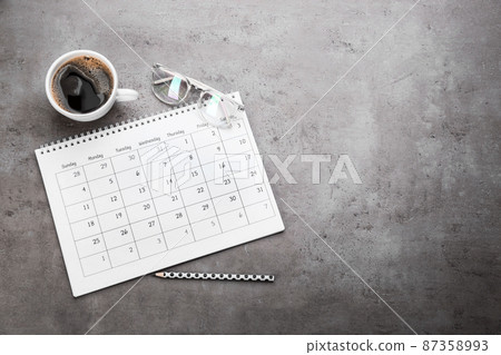 Flat lay composition with calendar and cup of coffee on grey stone table. Space for text Flat lay composition with calendar and cup of coffee on grey stone table. Space for text 87358993