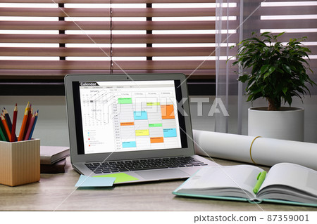 Laptop with calendar on wooden table in office Laptop with calendar on wooden table in office 87359001